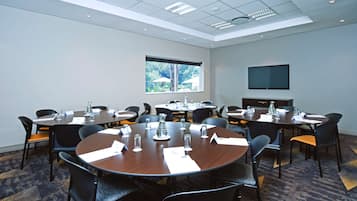 A conference room with multiple tables and chairs, equipped with nameplates and water glasses.