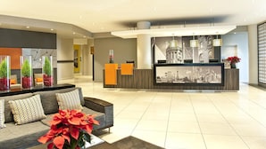Un moderno vestíbulo de hotel con mostrador de recepción, zona de estar y elementos decorativos.