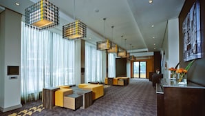 Un vestíbulo amplio con mobiliario moderno, ventanas grandes y lámparas colgantes decorativas.