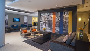 A modern lobby with a seating area, a large wall mural, and a flat-screen TV. - Garden Court Milpark (Johannesburg)
