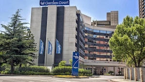 Un edificio moderno con un letrero que dice 'Garden Court', varias banderas y una entrada con portón.