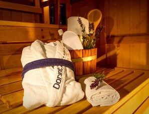 Eine hölzerne Bank mit einem Handtuch und einem Holzeimer, der ein Handtuch und Lavendelblumen enthält.