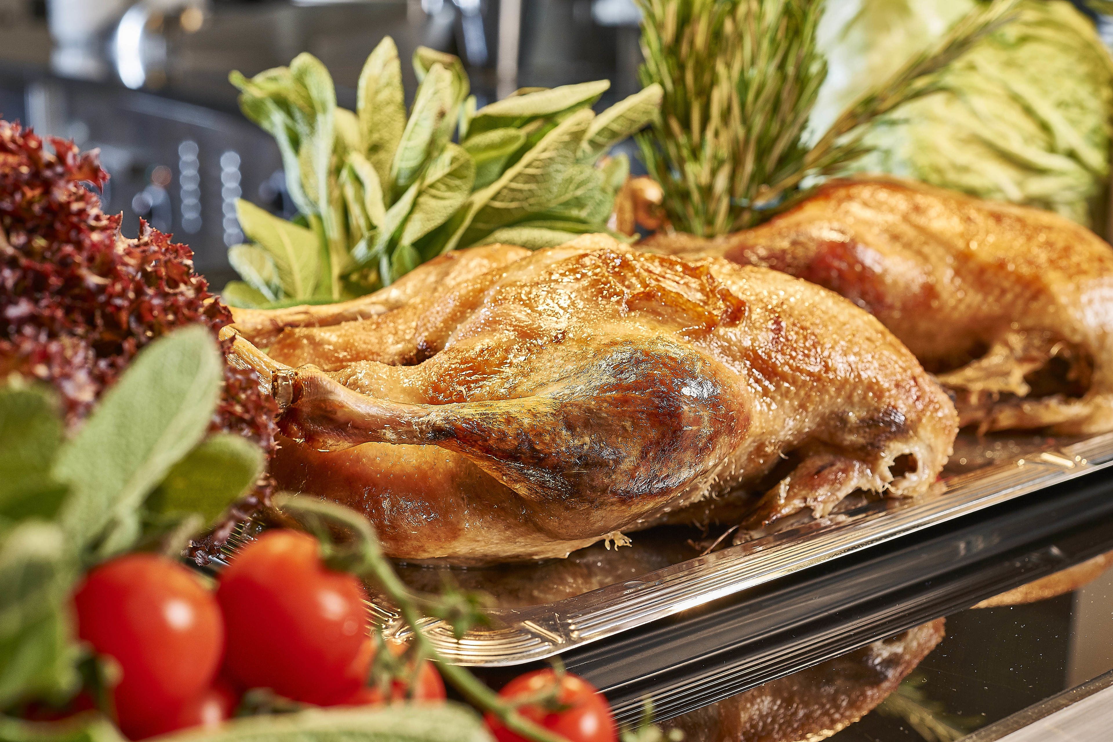 A roasted turkey surrounded by fresh vegetables and herbs.