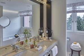 Ein modernes Badezimmer mit einem großen Spiegel, zwei Waschbecken und einem Schminktisch.