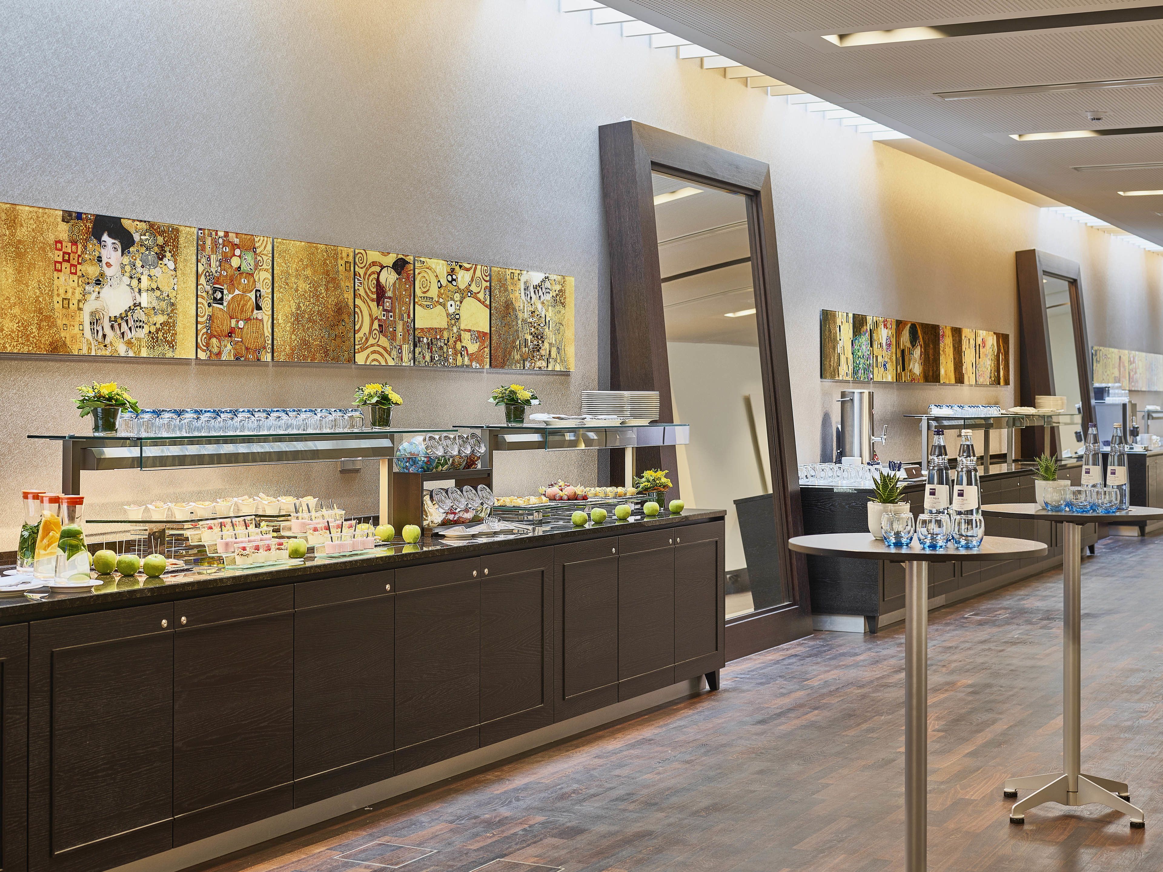 A buffet area with a variety of food and drink options, a large mirror, and artwork on the walls.
