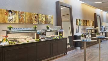 A buffet area with a variety of food and drink options, a large mirror, and artwork on the walls.