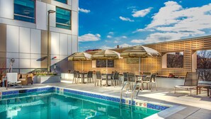 A pool area with a tiled edge, lounge chairs, and umbrellas. - Hyatt Place Washington DC/National Mall (Washington)