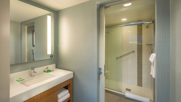 Un baño moderno con lavamanos, espejo y cabina de ducha de vidrio.