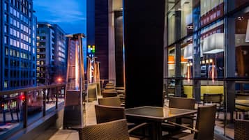 Terraza en la azotea con mobiliario exterior y vistas a edificios de la ciudad.