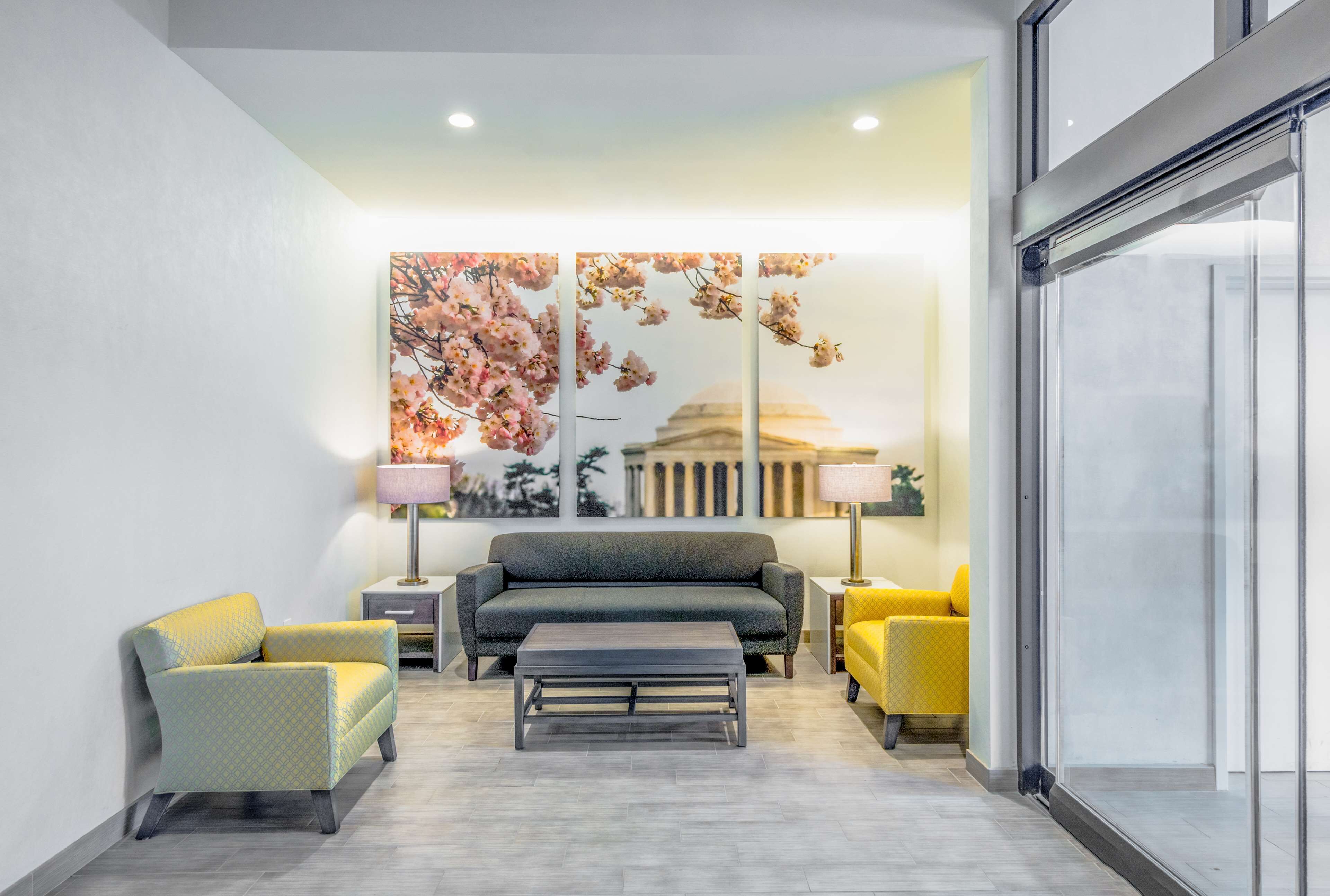 A modern living room with a sofa, two armchairs, a coffee table, and a large floral artwork on the wall.