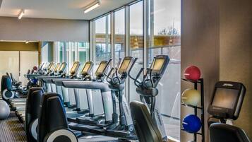 A gym with multiple treadmills, stationary bikes, and exercise balls.
