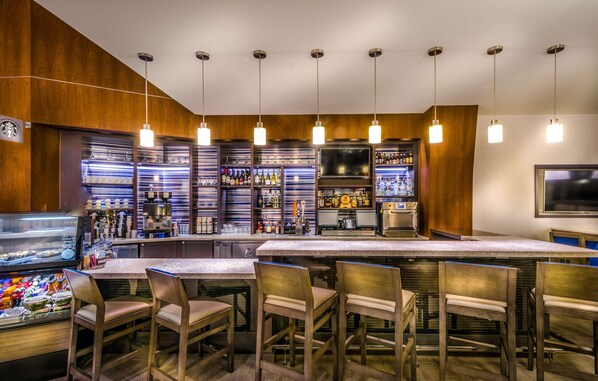 A bar area with wooden walls, a long counter, and multiple hanging lights. - Hyatt Place Washington DC/National Mall (Washington)