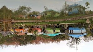A reflection of a houseboat with a blue roof, surrounded by greenery and a small dock.