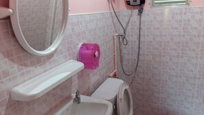 Et badeværelse med toilet, håndvask og brusebad med brusehoved.