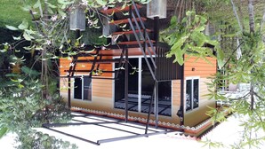 Une maison moderne avec une façade en bois, de grandes fenêtres et un balcon.