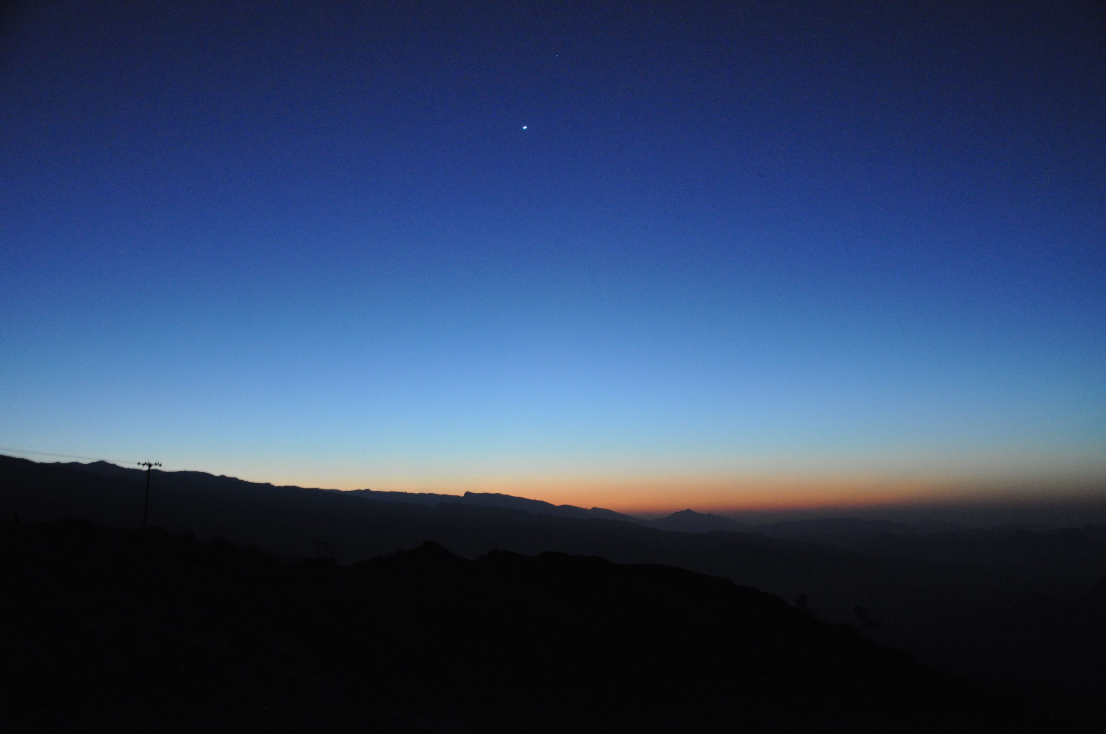 A mountain landscape at dusk with a clear sky.