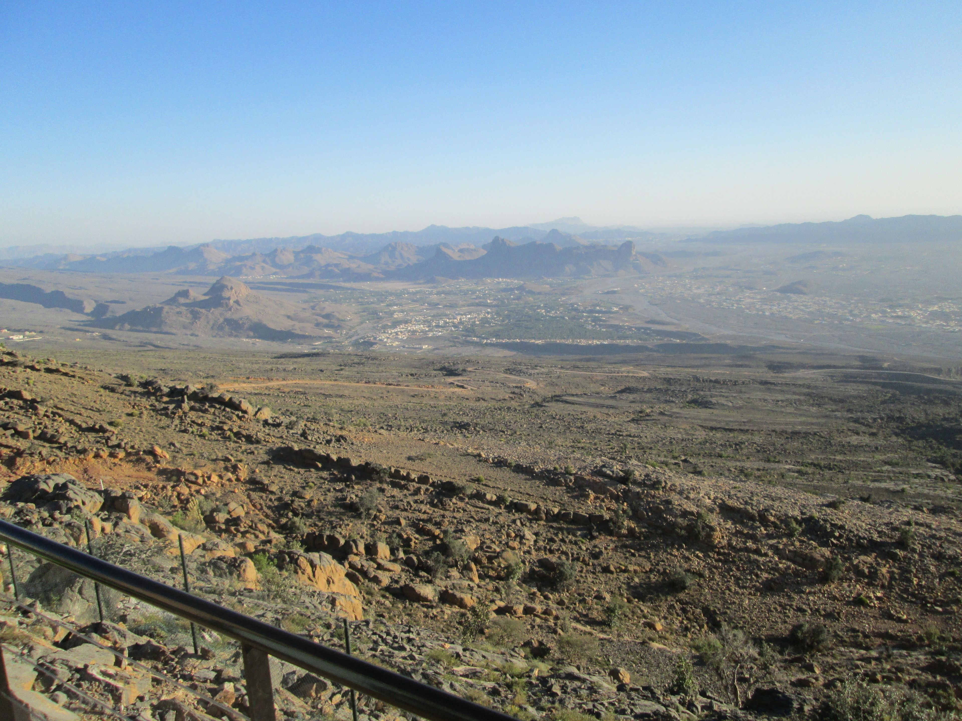 A panoramic view of a desert landscape with rocky terrain and distant mountains.