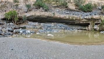 A rocky landscape with a small water body and a person standing in the foreground.