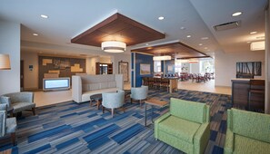 A hotel lobby with a reception desk, seating area, and a dining section. - Holiday Inn Express & Suites St John's Airport by IHG (St. John's)