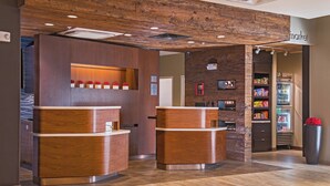 A reception area with wooden reception desks, a wall-mounted display, and a refrigerator stocked with beverages.