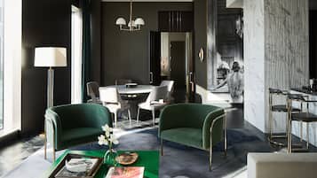 A modern hotel room with a dining area, a green sofa, a bar area, and a large mirror.