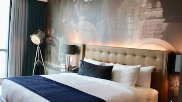A hotel room with a large bed, a nightstand, a lamp, and a wall with a mural.