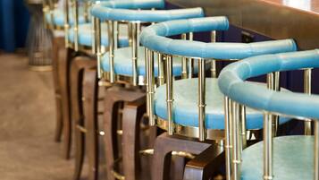 A row of bar stools with blue cushioned seats and wooden legs.