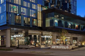 Ein Hotel mit moderner Glasfassade, Beschilderung mit 'Hotel Indigo' und einem Schild mit der Aufschrift 'Metropolis' als Ortsangabe.