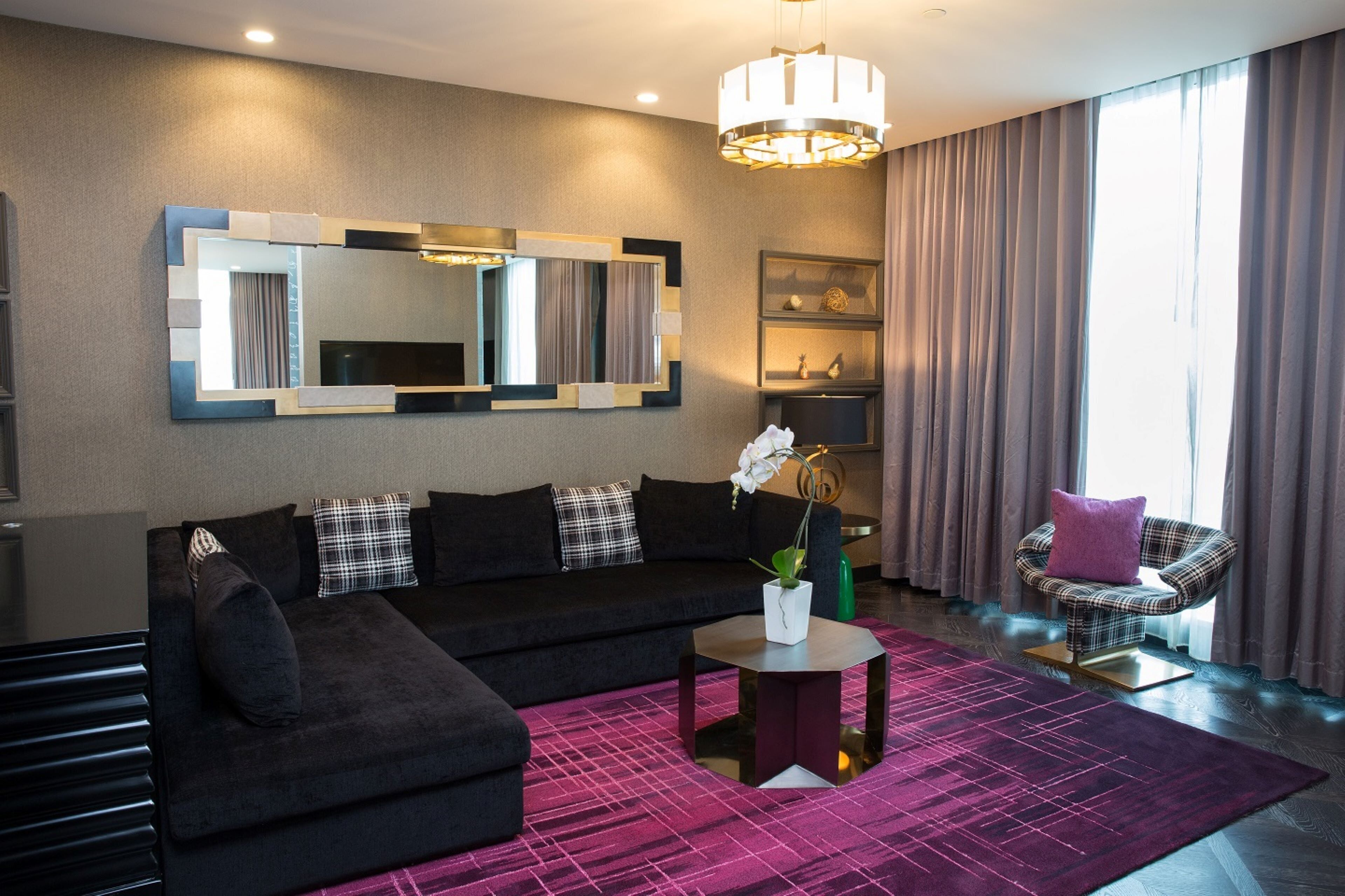 A modern living room with a sectional sofa, a coffee table, a large mirror, and a decorative plant.