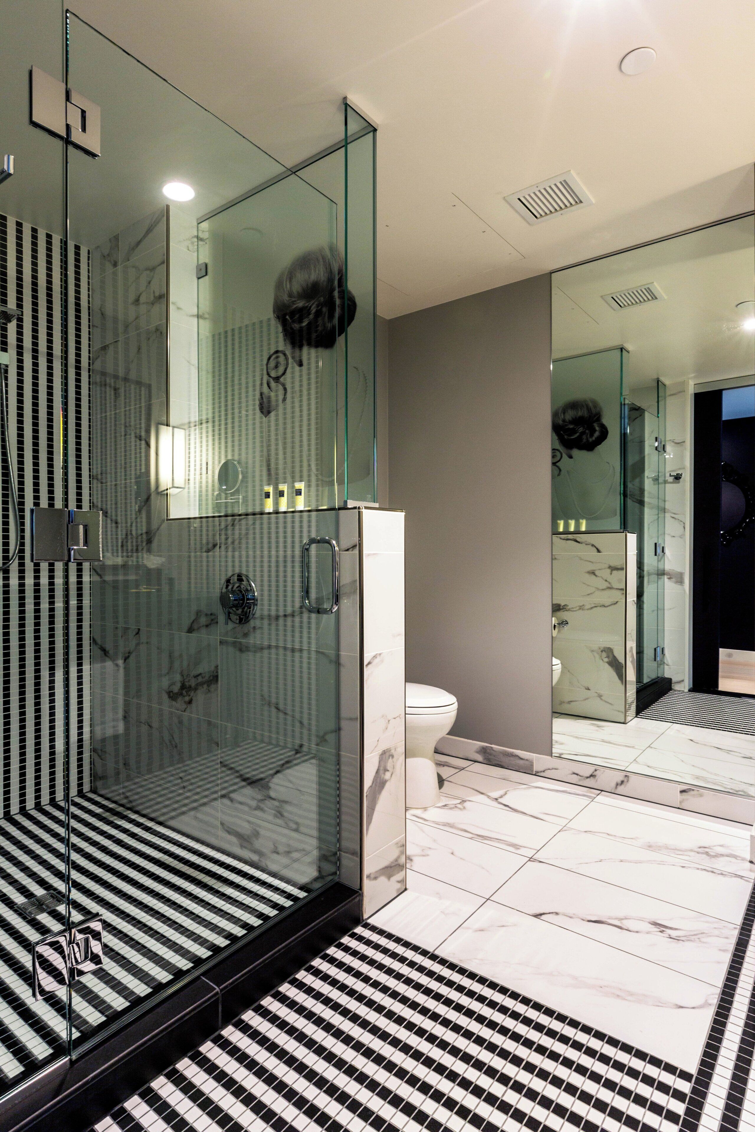 Ein modernes Badezimmer mit einer gläsernen Duschkabine, einer Toilette und einem Marmorboden.