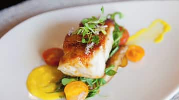 Une assiette contenant un morceau de poisson, des légumes verts et une sauce jaune.