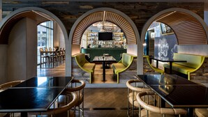 Una zona de bar moderna amb un mostrador central, seients verds i detalls de fusta.