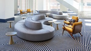 Un interior modern amb una zona d'estar central, una escala i grans finestres.