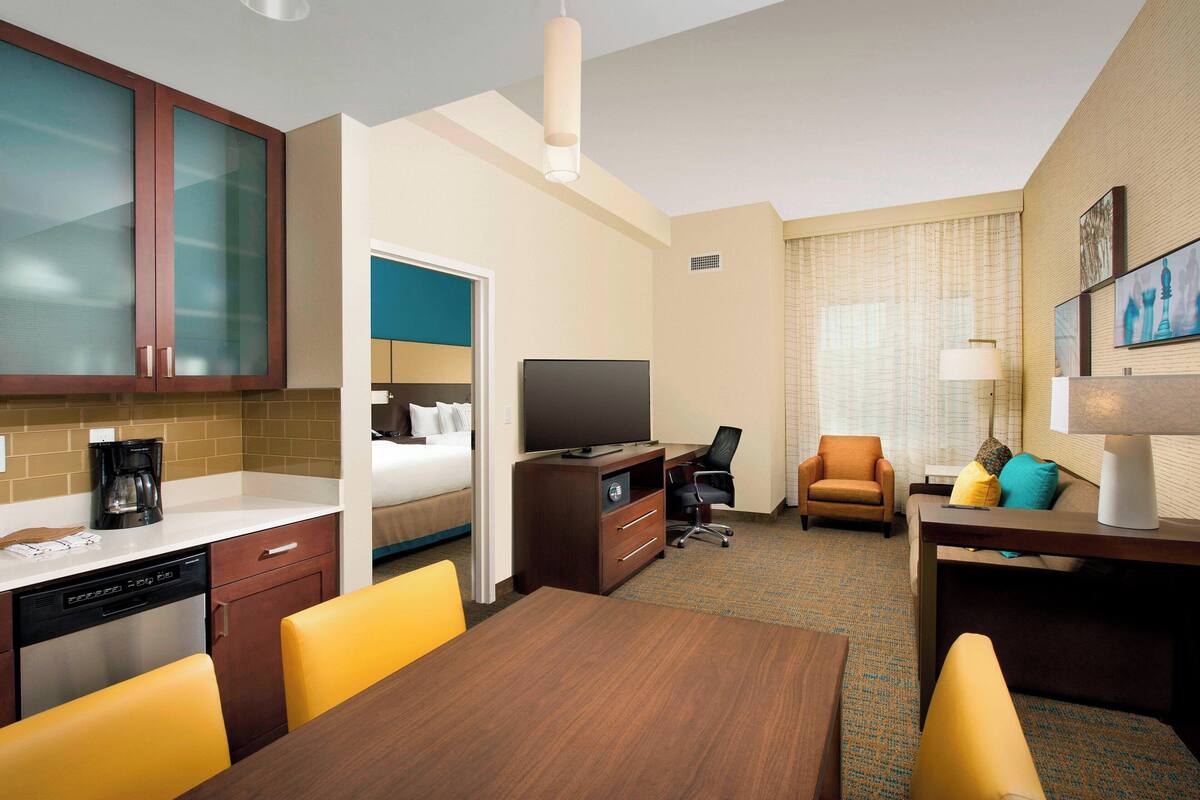 Ein Hotelzimmer mit Essbereich, Fernseher, Schreibtisch und Bett.