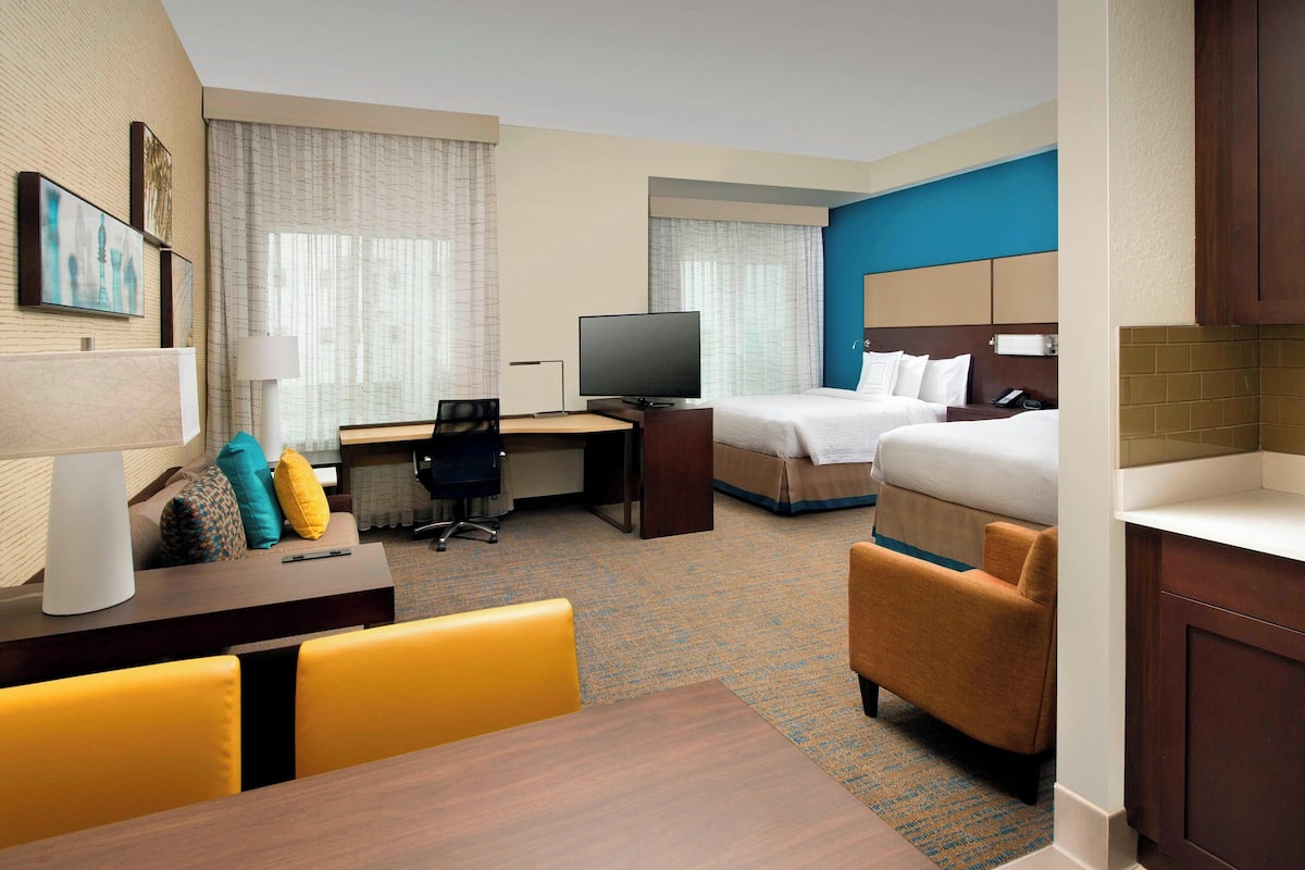 Ein Hotelzimmer mit Bett, Schreibtisch, Stuhl, Fernseher und einem kleinen Tisch.
