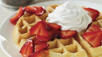 Un plato de gofres cubiertos de fresas y crema batida.