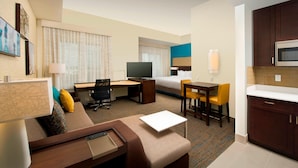 Ein Hotelzimmer mit Bett, Schreibtisch, Stuhl, Fernseher und einer Küchenzeile.