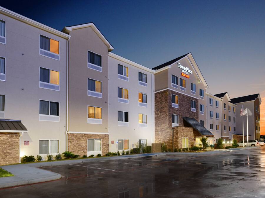 A hotel with multiple floors, a parking lot, and a sunset in the background.
