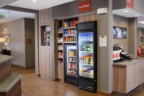 Een hotel lobby met een automaat voor drankjes, een receptiebalie en een bord dat de locatie van het toilet aangeeft.