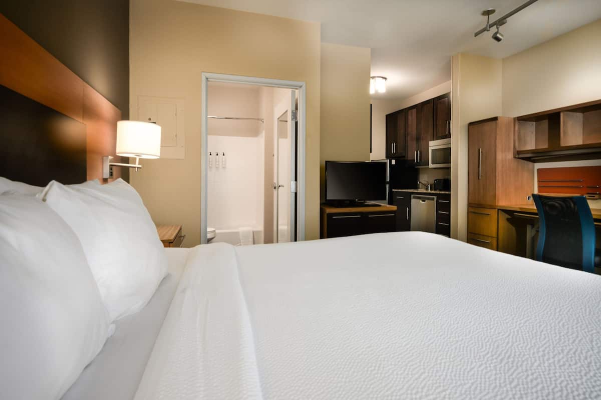 Habitación de hotel con una cama grande, un escritorio, un microondas y una kitchenette.