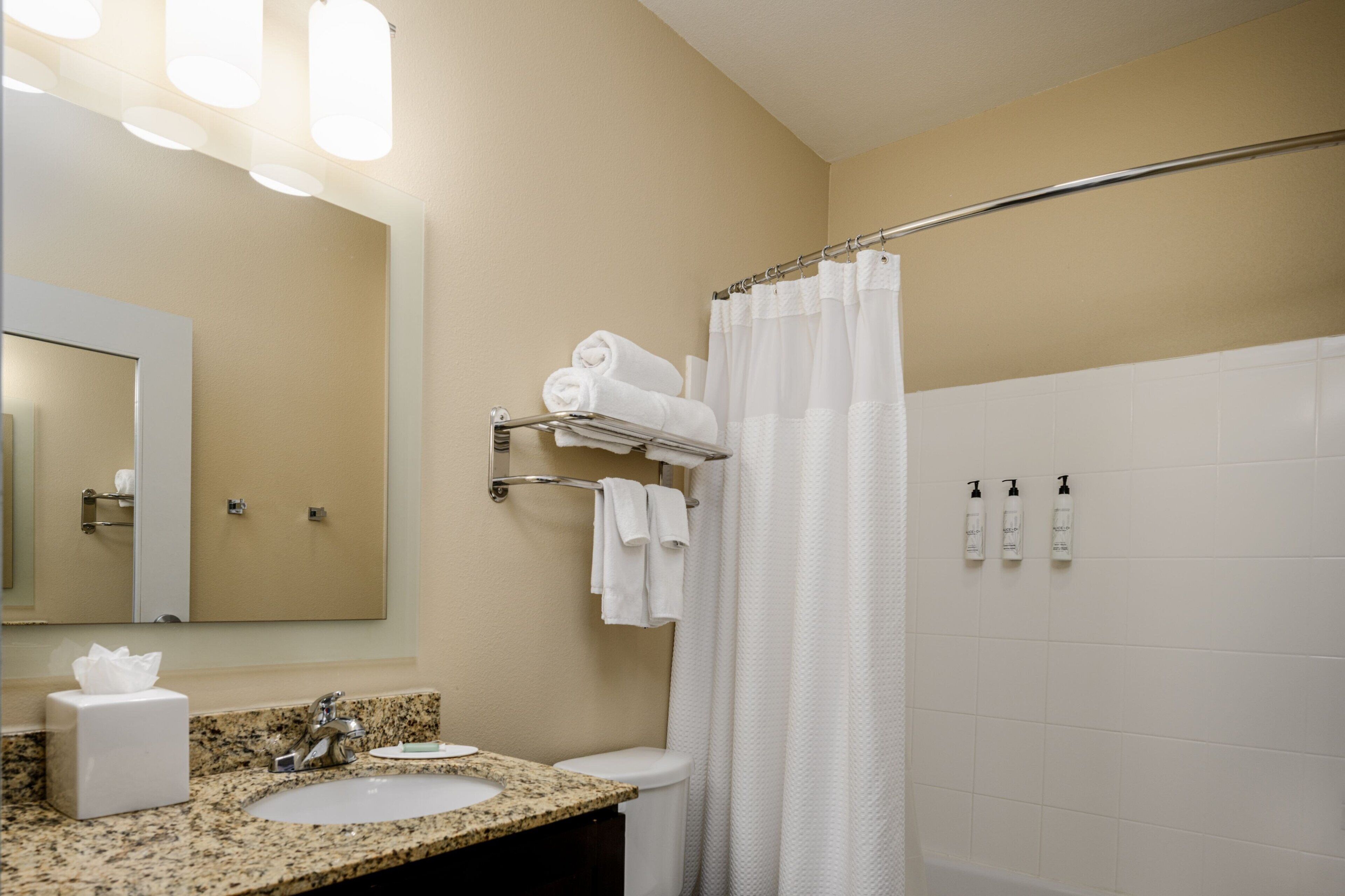 A bathroom with a sink, mirror, towel rack, and shower curtain.