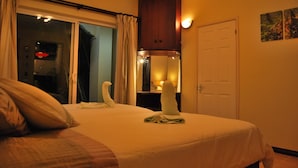 A hotel room with a bed, a wooden cabinet, a door, and a window with curtains. - Marisa Residences (La Gaulette)