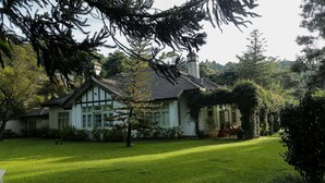 Une maison traditionnelle avec une pelouse bien entretenue et des arbres qui l’entourent.