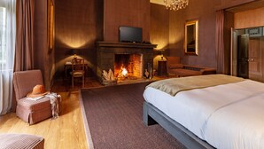 Une chambre à coucher avec une cheminée, une télévision, un lit et un lustre.