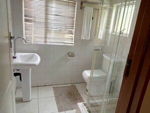 Un baño con lavamanos, inodoro y cabina de ducha.