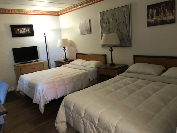 A hotel room with two beds, a TV, bedside lamps, and artwork on the walls. - Motel Bellefeuille (Trois-Rivieres)