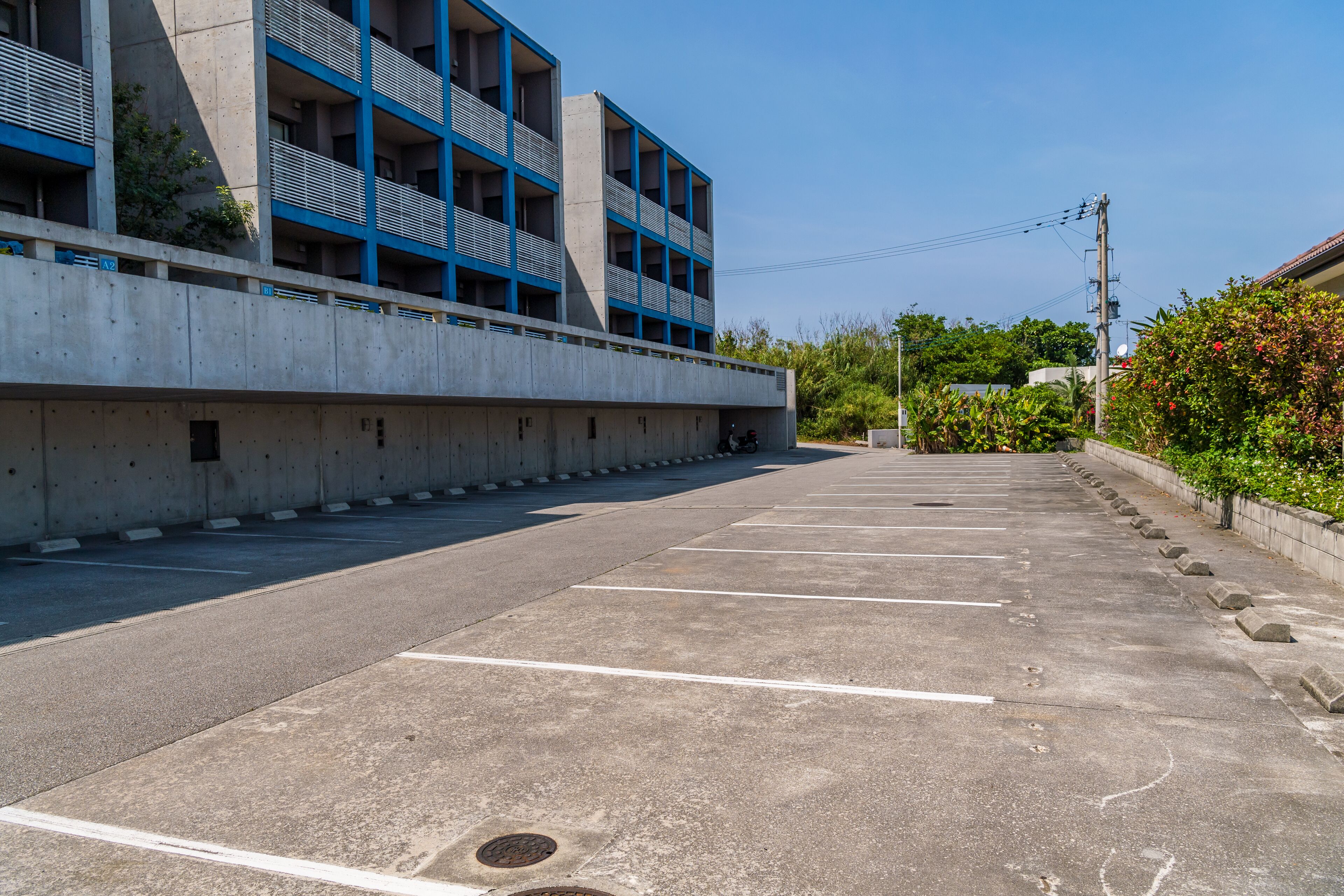 A parking lot with concrete barriers and a building with blue accents in the background.