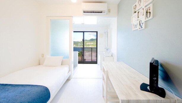 A modern hotel room with a bed, a desk, and a view of the outdoors. - HOTEL E-horizon Resort Condominium Sesoko (Motobu)