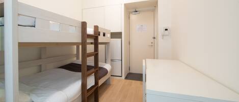 A bunk bed room with a desk and a door.