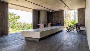 An open-plan room with a concrete platform, wooden flooring, and a bicycle. - HOTEL E-horizon Resort Condominium Sesoko (Motobu)